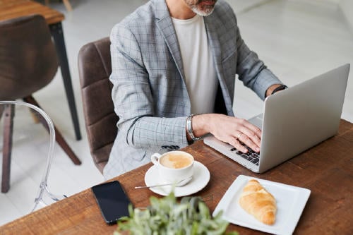 Businessman Using A Laptop In A Cafe Businessman Using A Laptop In A Cafe